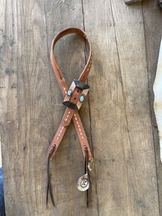 a brown and white dog leash laying on top of a wooden floor next to a person's foot