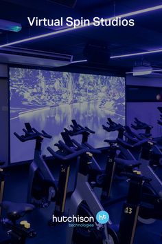 a room with rows of exercise bikes in front of a projector screen that reads virtual spin studios