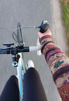 the person is riding their bike down the street with her hand on the handlebars