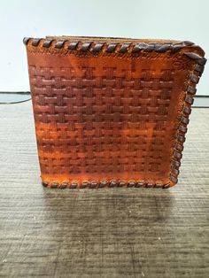 a brown leather basket sitting on top of a wooden floor