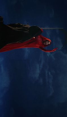 a man flying through the air on top of a red kite under a cloudy blue sky