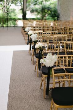 rows of gold chairs with black seats and white flowers