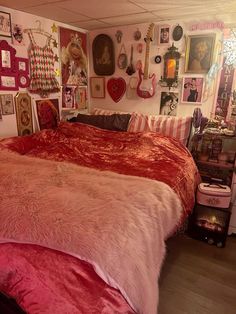 a bedroom with pink and red bedding, pictures on the wall and other decorations