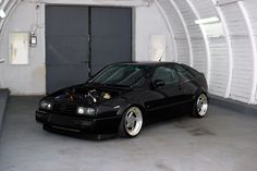 a black car parked in a garage with its hood up and the engine on it's side