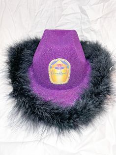 a purple hat with black fur around it on a white sheeted surface and the logo of an ice cream company