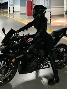 a woman in black riding on the back of a motorcycle