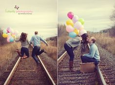 two people sitting on train tracks with balloons in the air and one person holding a suitcase