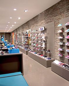 the inside of a shoe store filled with lots of different colored shoes on display in front of a brick wall