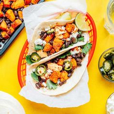 two tacos with black beans, avocado and cilantro on a plate