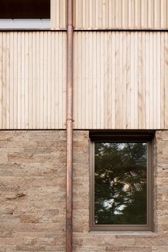 a window on the side of a building with a wooden pole in front of it