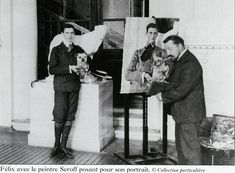 two men standing next to each other in front of an easel with pictures on it