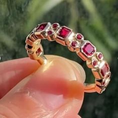 a person is holding a ring with red stones on the inside and outside of it