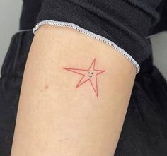 a small red star tattoo on the back of a woman's left arm