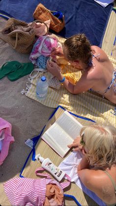 two women are sitting on the beach reading and having fun with each other while wearing bikinis