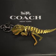 the coach keychain is shaped like a dinosaur