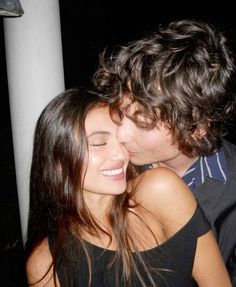 a man and woman kissing each other in front of a pole with their eyes closed