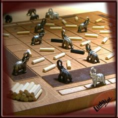 a board game with elephants and dominos on the board, surrounded by pieces of wood