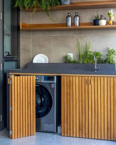 a washer and dryer in a room with plants on the shelves above it