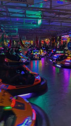 several bumper cars are lined up in a brightly lit indoor area with neon lights on the ceiling