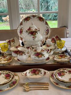 the table is set with many plates and silverware, including an antique teapot