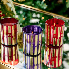 three colorful candles sitting on top of a table next to a christmas ornament