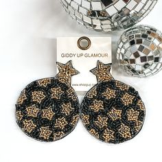 Black circle beaded circles with a gold beaded star at the top. The circle has gold beaded star design. These earrings are pictured on a white background with disco balls at the top right corner of the picture. Gold Black Enamel Earrings For Evening, Black Moon Shaped Celestial Earrings, Black Star-shaped Earrings For Party, Black And Gold Beaded Drop Earrings, Cheap Black Star-shaped Earrings, Black Beaded Earrings, Center Of Attention, Giddy Up Glamour, Gold Star