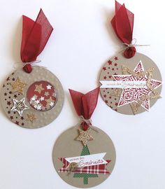 three christmas ornaments hanging from red ribbons