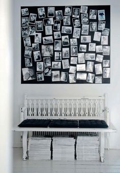 a white bench sitting in front of a black and white wall with pictures on it