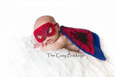 a baby wearing a spider man costume laying on top of a white blanket with his eyes closed