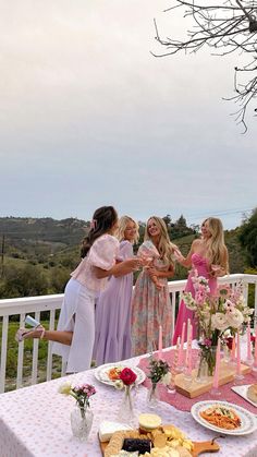 a group of women standing around a table with food and drinks on top of it