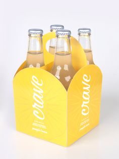 four bottles of soda sitting in a yellow box on a white surface with the lid open