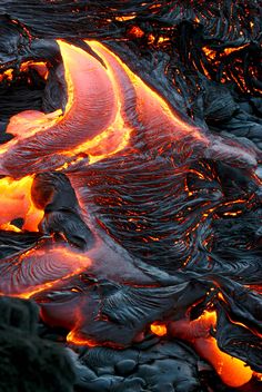 lava flowing down the side of a mountain with orange light coming from it's sides