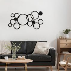 a living room with a black leather couch and coffee table in front of a white wall