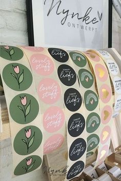 several rolls of pink and green stickers on display in front of a sign that says, mynke on it