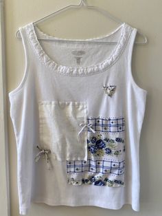 a white top with blue flowers on it hanging from a hanger next to a door