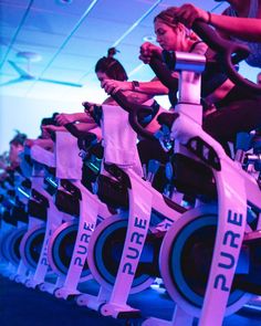 there are many people riding exercise bikes in the gym with pink ribbon around their ankles