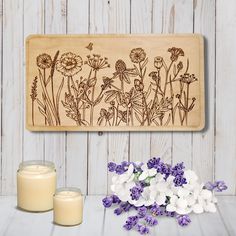 a wooden plaque with flowers and candles on a white table next to some lavenders