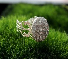 a close up of a ring on some green grass in the daytime light, with small crystals