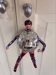 a woman is hanging upside down in front of a mirror ball