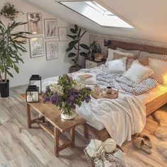 a bed sitting under a window next to a wooden table with flowers on top of it