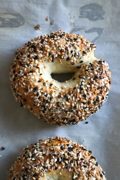 two sesame seed bagels sitting on top of a piece of wax paper