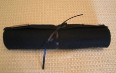 a roll of black fabric tied up on top of a bed