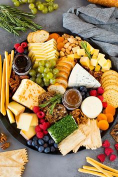 a platter filled with cheese, crackers and fruit on top of a table