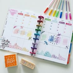 an open planner with markers and stickers next to it