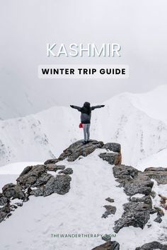 a person standing on top of a snow covered mountain with their arms outstretched in the air