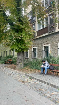 a man sitting on a bench in front of a building