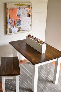 a wooden table with two benches in front of it and pictures on the wall behind it