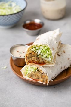 two burritos on a plate with dipping sauce