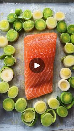 raw salmon surrounded by artichokes and other vegetables on a sheet of metal