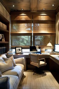 a home office with two computer desks and a couch in front of the window